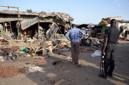 A police officer stands at the scene of a bombing after at least 20 people were killed when a young female suicide bomber detonated her explosives at a bus station in Maiduguri, northeast Nigeria, on June 22, 2015 in an attack likely to be blamed on Boko Haram.  The blast happened near a fish market in the Baga Road area of the city, which has been repeatedly targeted in recent weeks by shelling, bombs and suicide attacks.  AFP PHOTO/STRINGER        (Photo credit should read STRINGER/AFP/Getty Images)