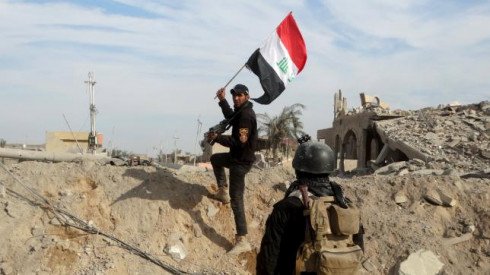 A member from the Iraqi security forces holds an Iraqi flag in the city of Ramadi, December 27, 2015. REUTERS/Stringer
