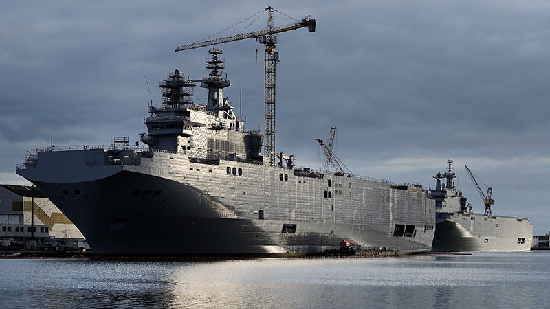 A picture shows the Sevastopol (L) and the Vladivostok  warships, two Mistral class LHD amphibious vessels ordered by Russia from STX France in Saint-Nazaire, western France, on December 20, 2014. Russia will gladly take back the money it paid for French Mistral-class warships whose handover has been delayed by concerns over Moscow's role in the Ukraine crisis, deputy defence minister Yury Borisov has said. France, which is struggling economically, is faced with a tough decision: deliver the two mammoth warships to Russia and face the wrath of its NATO allies or end up with two vessels equipped for the Russian navy and pay the price and possibly heavy fines. AFP PHOTO / JEAN-SEBASTIEN EVRARD        (Photo credit should read JEAN-SEBASTIEN EVRARD/AFP/Getty Images)