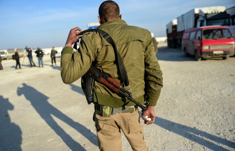 A Syrian opposition fighter keeps watch as Syrians fleeing Aleppo wait on February 5, 2016 in Bab-al Salam, next to the city of Azaz