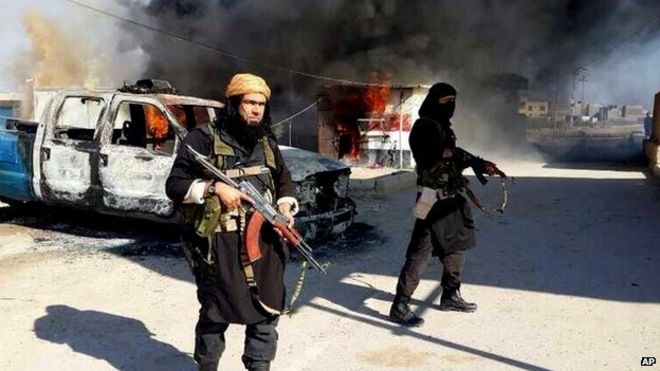 ISIS militants stand in front of a burning truck in Iraq