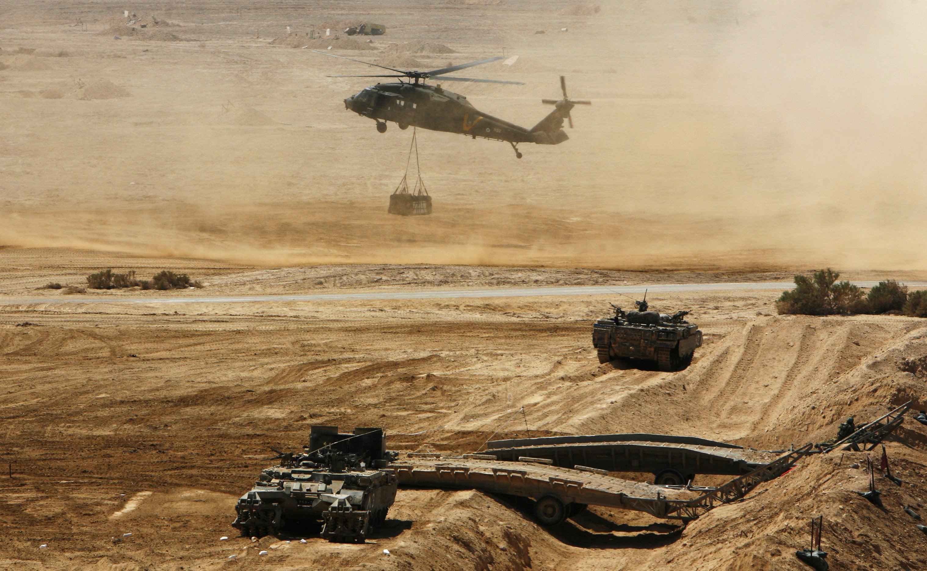 FILE - In this Sept. 16, 2008 file photo, an Israeli helicopter is seen flying above armored vehicles during an army exercise at the Shizafon Army Base in southern Israel. The Israeli military in 2012 is embarking on its biggest construction project in three decades, moving 10,000 soldiers out of some of the country's priciest real estate to a massive new base it is building in the desert sands of southern Israel. (AP Photo/Tara Todras-Whitehill, File)