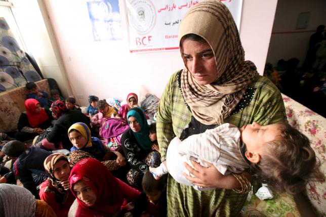 A displaced woman carries her child in a building that is used as a temporary shelter in Makhmour area, southeast of Mosul.  REUTERS/Azad Lashkari
