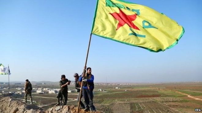 Kurdish Popular Protection Units (YPG) raise its flag on a hill overlooking Kobane