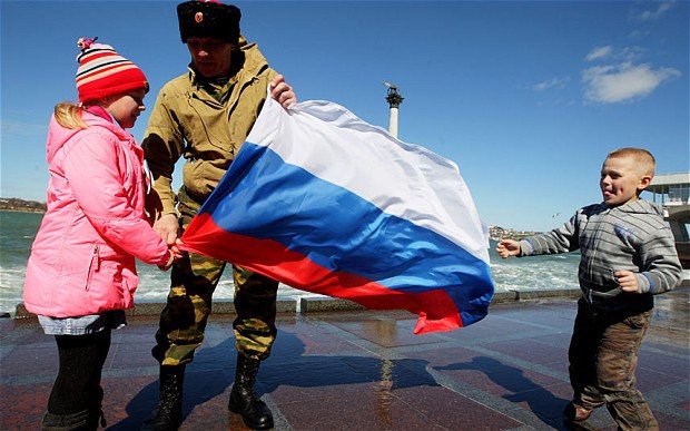A man with two children hold the Russian flag on the coast of the bay of Sevastopol, Crimea, Ukraine Photo: Zurab Kurtsikidze/ EPA