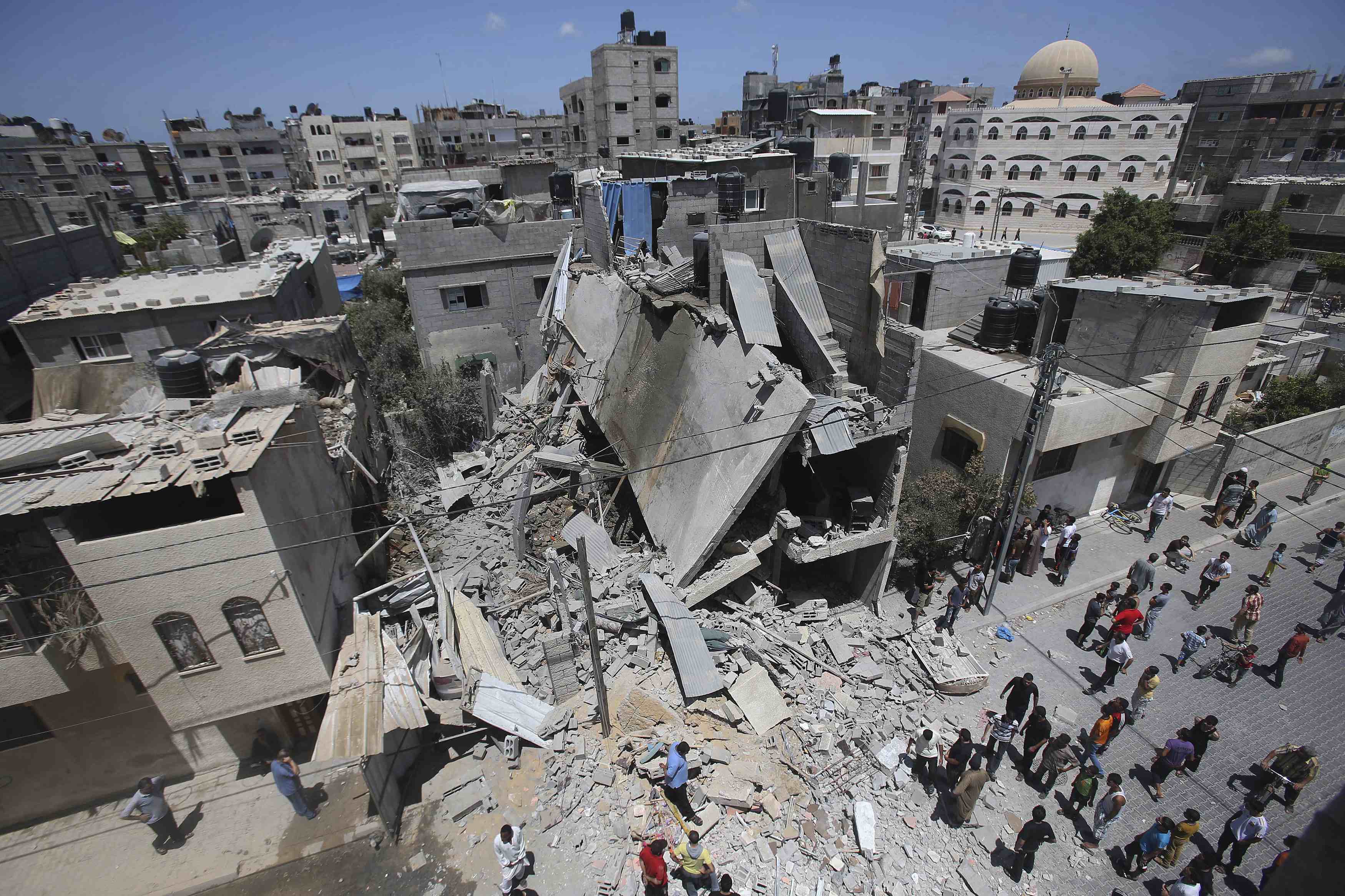 Palestinians in Rafah, Gaza Strip, gather around the remains of a house that police said was destroyed in an Israeli airstrike. Israel said it shot down a drone from Gaza July 14, the first reported deployment of an unmanned aircraft by Palestinian militants whose rocket attacks have been regularly intercepted. (CNS photo/Ibraheem Abu Mustafa) (July 14, 2014) See GAZA-TARAZI July 14, 2014.