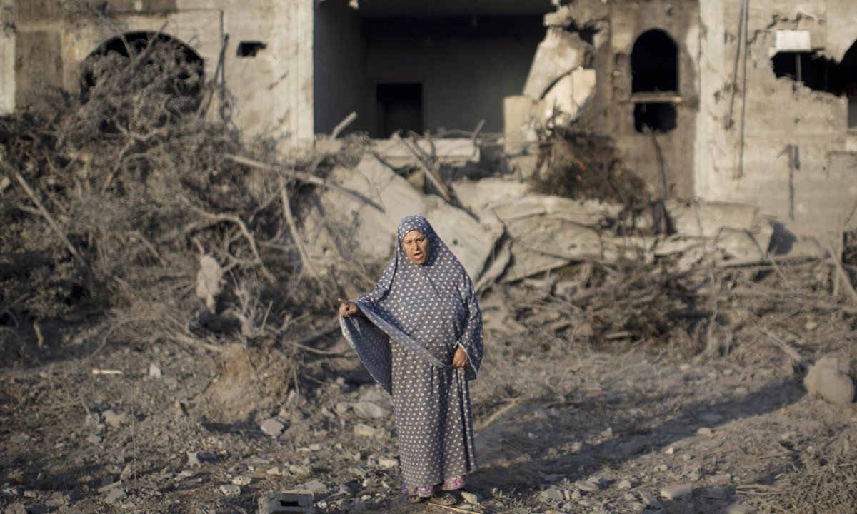 A Palestinian woman gestures as she stands amidst destruction following an Israeli military strike in  Gaza City on July 08, 2014 . AFP PHOTO / MAHMUD HAMS