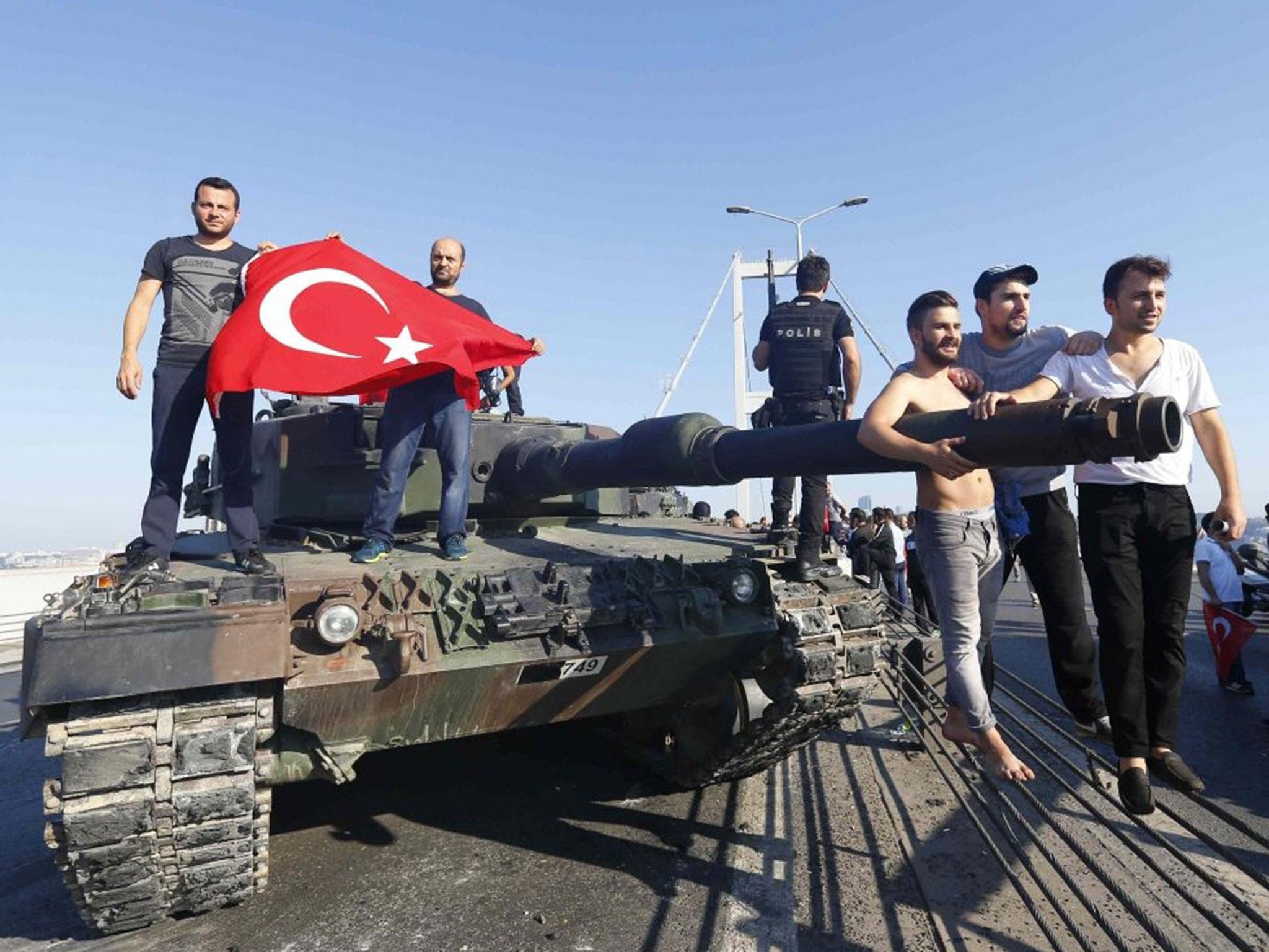 Civilians carry the Turkish flag onto a tank abandoned by rebel soldiers Reuters