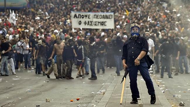 A protestor gestures to police near the Parliament building in Athens where a bank was firebombed, killing three people / AFP Source: AFP