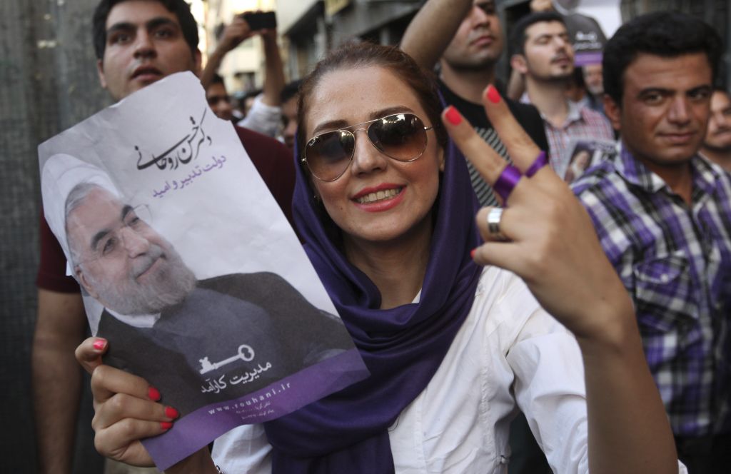 A female supporter of Iranian presidential candidate Hasan Rowhani flashes a victory sign as she holds his poster during a celebration gathering in Tehran, Iran, Saturday, June 15, 2013 (photo credit: AP/Vahid Salemi)