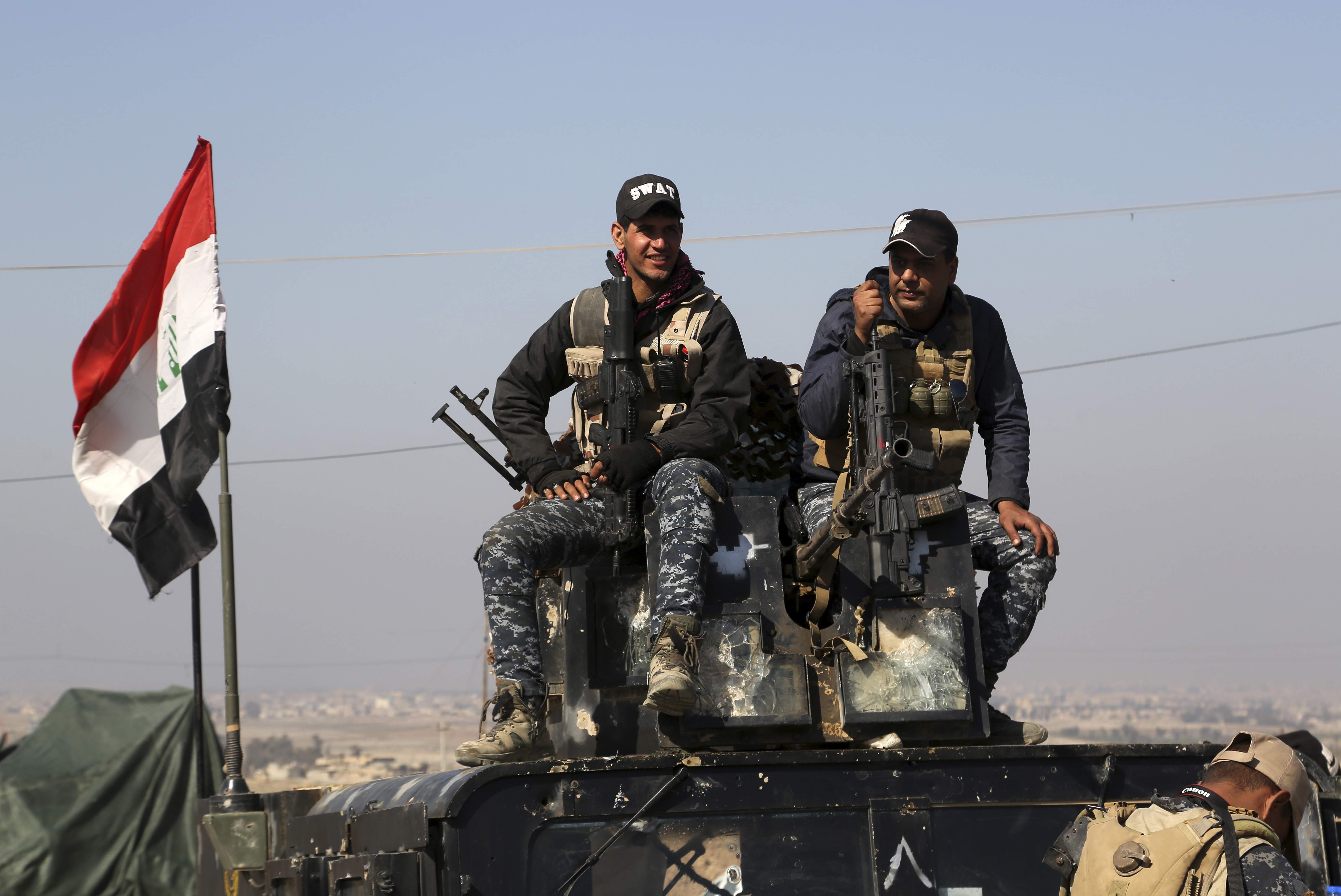 Two policemen sit atop of their armoured vehicle as Iraqi Federal police deploy after regaining control of the town of Abu Saif, west of Mosul. (Photo | AP)